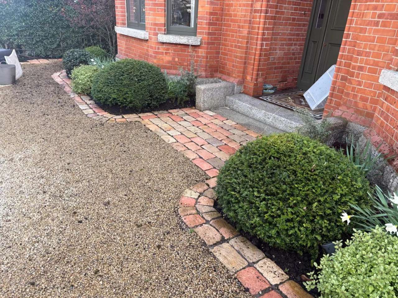 Cobble edged front path of a red-brick house after cleaning
